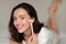 Glad caucasian millennial woman applying powder with brush on face, lies on bed