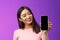 Glad cheerful good-looking young asian woman smiling satisfied hold smartphone, show phone screen look phone display