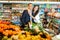 Glad couple is standing with cart with products in supermarket