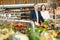 Glad couple is standing with cart with products in supermarket