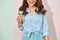 Glad delightful young asian woman with toothy smile looks at camera, holds tasty ice cream, stands on light pink background in
