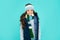 glad emotional kid with curly hair in hat and scarf. teen girl on blue background.