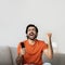 Glad excited millennial middle eastern male with open mouth and remote control makes gesture