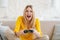 Glad excited pretty young blonde european female in yellow clothes with open mouth plays online games