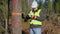 Glad forest engineer with tablet PC near the tree