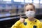 Glad and happy beautiful joy child in the medical helthcare guarding or protecting mask and in yellow t-shirt in the tube, subway