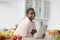 Glad millennial african american lady in casual with tablet in kitchen interior at table with vegetables