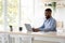 Glad millennial african american man with beard in glasses chatting remotely, work on computer alone