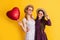glad mother and daughter hold love heart balloon on yellow background
