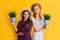 glad mother and daughter with potted plant on yellow background