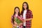 glad mother and daughter with tulip flowers on yellow background