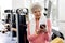 Glad retiree looking at mobile in gym