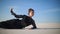 Glad woman in black dress lies on white sand, relaxes and enjoys in desert