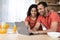 Glad young african american wife and husband have breakfast in morning together, enjoy chat, watch video