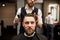 Glad young man having hair cut at barber salon