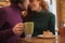 Glad young man and woman drinking hot beverage in cafe
