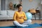 Glad young pregnant african american woman touching big belly and enjoying baby move, practicing yoga