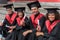 Glad young students sitting on steps in graduation clothes