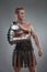 Gladiator in armour posing over grey background