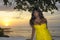 Glamorous African American black woman in chic and elegant summer dress posing relaxed on summer sunset beach