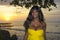 Glamorous African American black woman in chic and elegant summer dress posing relaxed on summer sunset beach