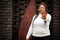 Glamorous african american woman in white turtleneck sweater pose at street show stop sign by hand