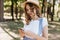 Glamorous curly girl in trendy clothes looking at phone screen. Outdoor shot of fascinating female