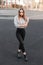 Glamorous modern young woman in black stylish jeans in a striped elegant blouse in trendy leather shoes posing on an open