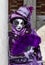 Glamorous woman performer with purple costume and venetian mask during venice carnival