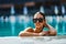 Glamorous woman in stylish sunglasses enjoying swimming in turquoise water.