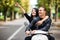 Glamorous young couple riding scooter in the street, Woman pointed on side, man look in same way