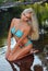 Glamour blond model with body in blue bikini posing pretty at the nature location