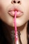 Glamour closeup of woman`s lips drinking with pink straw. Natural makeup. Fashion summer look with bottle of water