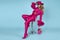 Glamour elegant woman is wearing an elegant fuchsia suit, hat and a pink handbag with spring flowers and is posingob blue