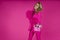 Glamour elegant woman is wearing an elegant fuchsia suit and a pink handbag with spring flowers and is posing against a pink