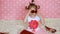Glamour. Fashion. Fashionista. Cute little girl dresses red sunglasses in the shape of hearts. Pink background. Funny