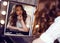 Glamour girl with dark curly hair making makeup, paints her lips, looking at mirror