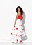 Glamour gorgeous woman model latin dancer wearing red white dress with flower print posing for camera at light