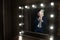 Glamour guy in elegant suit and comical mask looks at himself in the mirror