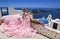 Glamour, stylish elegant bride woman in pink long wedding dress is posing near Church of the Three Bells in Fira in Santorini