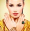 Glamour woman with beautiful golden nails and emerald ring