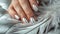 Glamour woman hand with luxury silver color nail polish manicure on fingers, touching silver feathers