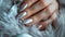 Glamour woman hand with luxury silver color nail polish manicure on fingers, touching silver feathers