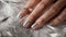 Glamour woman hand with luxury silver color nail polish manicure on fingers, touching silver feathers