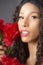 Glamourous studio portrait of young Latina woman holding red flowers