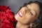 Glamourous studio portrait of young Latina woman holding red flowers