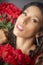 Glamourous studio portrait of young Latina woman holding red flowers