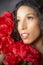 Glamourous studio portrait of young Latina woman holding red flowers