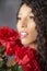 Glamourous studio portrait of young Latina woman holding red flowers