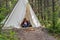 Glamping trip - woman sitting and relaxing in canvas teepee on campsite